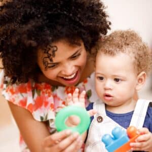 Mother and infant playing with colorful ring toys.