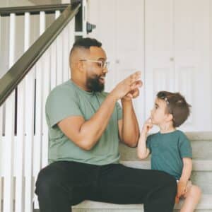 Man and little boy practicing sign language.