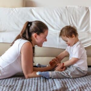 Mother and little boy on floor playing while mother uses a positive communication style to affect his development.