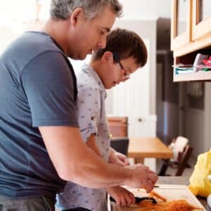 Father and son cooking together and taking turns as they communicate and cook.