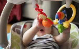 Infant engaged in hands-on play with colorful toys.