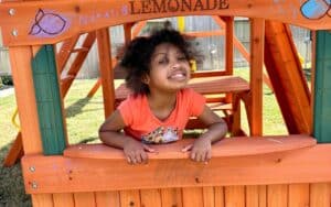 Little girl pretending at lemonade stand smiling.