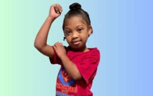 Little girl flexing muscle showing strength for Special Olympics.