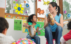 Little girl and speech pathologist playing tambourine and singing together.
