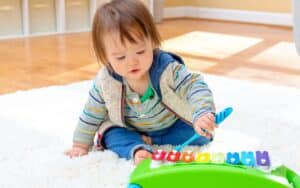 Infant playing a toy xylophone.