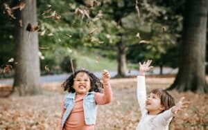 Children listening to nature's music as they play in fall leaves.