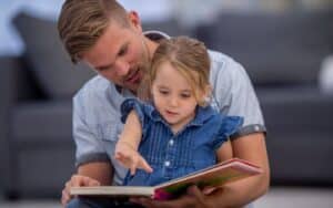 Father explaining something in a book to his daughter.